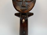 une vieille sculpture en bois représentant un homme coiffé d'un chapeau