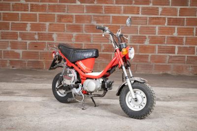 a small red motorcycle parked in front of a brick wall