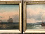 une paire de peintures à l'huile représentant des bateaux sur une plage, accrochées près d'un mur