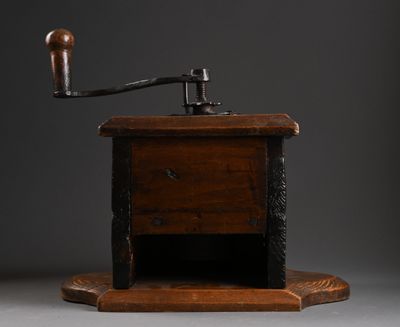 un vieux moulin à café avec un socle et une poignée en bois