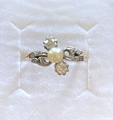 une bague sertie d'une perle, posée sur un tissu blanc