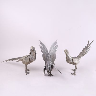 trois oiseaux en métal sont placés les uns à côté des autres sur une surface blanche