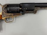 un vieux revolver avec une poignée en bois sur une surface blanche