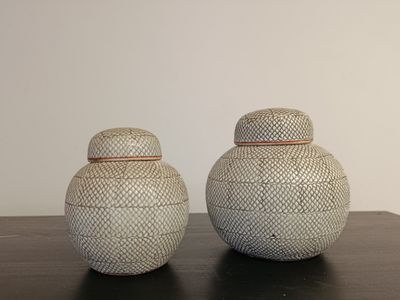 two white vases sitting on top of a table next to each other