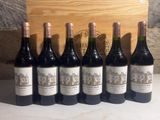 six bottles of wine are lined up in front of a wooden box