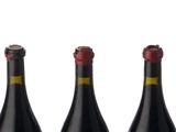 four bottles of wine lined up in a row on a white surface