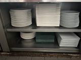 de nombreuses assiettes empilées sur une étagère métallique dans la cuisine