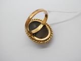 gros plan d'une bague en or contenant une pierre noire