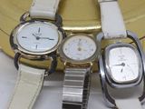 three watches sitting next to each other on a white surface