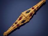 a close up of a gold and ruby broochle on a blue background
