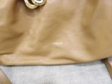 beige leather handbag with a gold metal ring on the handle