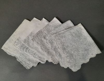 quatre serviettes blanches ornées de dentelle posées sur une table