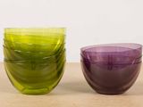 purple and green glass bowls sitting next to each other on a table