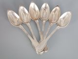 six silver spoons are arranged in a row on a gray surface