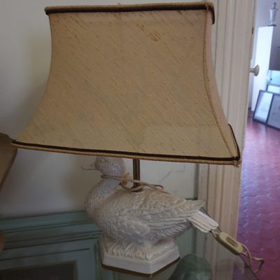 une lampe ornée d'un oiseau, posée sur une table en verre