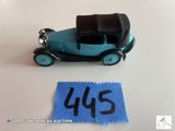 une petite voiture miniature posée à côté d'une feuille de papier bleue