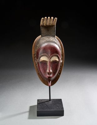 un masque en bois sur un support avec un fond noir