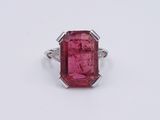 a close up of a pink tourmaline and diamond ring on a white surface