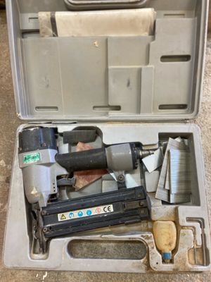 an open tool box with a stapler and a nail gun in it