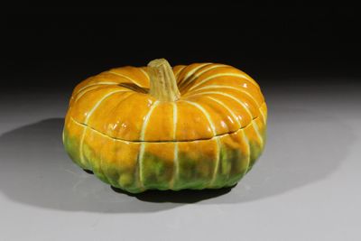 une boîte en forme de citrouille, jaune et verte, posée sur une table
