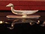 a silver duck sitting on top of a red suitcase