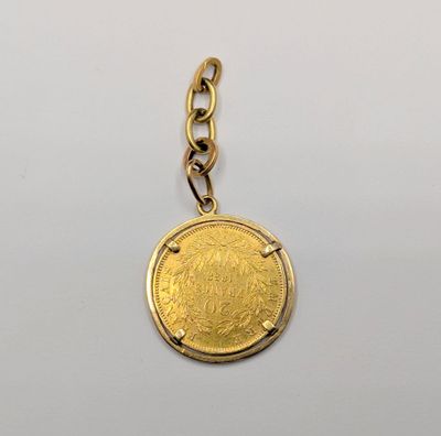 a close up of a gold coin on a chain on a white surface