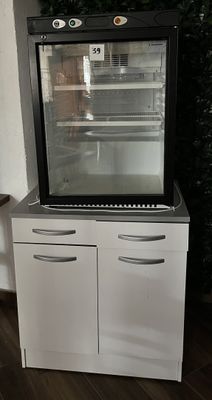un petit réfrigérateur avec une porte vitrée, dans un coin de la pièce