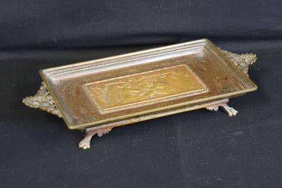 brass plate with ornate design on top of it on a black background