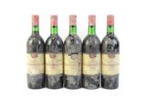 quatre bouteilles de vin sont alignées sur une surface blanche