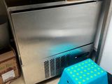 un tabouret bleu devant un réfrigérateur en acier inoxydable