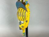 a close up of a yellow and blue sculpture on a black stand