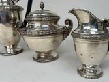 three silver teapots sitting on a white table
