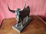 a statue of a bull that is on a wooden table