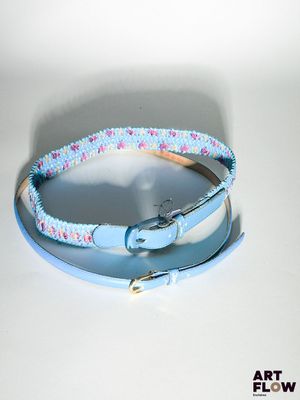 un collier de chien muni d'une boucle métallique posé sur une table blanche