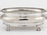 une assiette en argent ancienne avec des poignées et des poignées sur un support