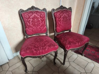 two red chairs sitting next to each other on a tiled floor