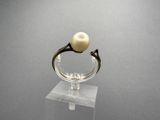 a ring with a pearl on top of a clear stand