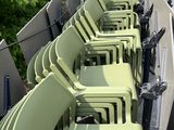 many green chairs lined up in a row on the side of the road