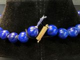 blue lapis beaded necklace with a feather charm on a black mannequin