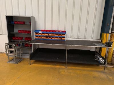 an image of a kitchen area with a table, shelves, and bins