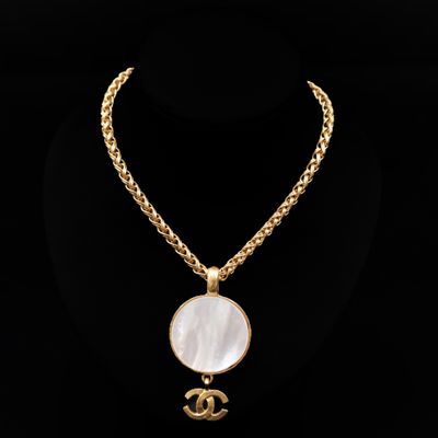 un collier à chaîne en or orné d'un pendentif en nacre blanche