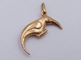 a close up of a gold bird pendant on a white surface