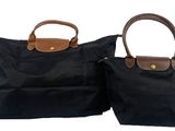 two black bags with brown handles sitting side by side