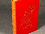 an orange book sitting on top of a table next to a red book