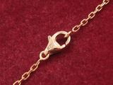 a close up of a gold chain with a clasp on a red velvet surface