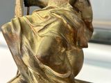 bronze statue of a woman sitting on a chair holding a umbrella