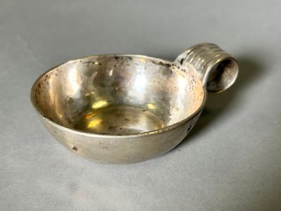 a small silver bowl with a handle on a table