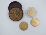 deux pièces d'or et un petit récipient en verre sur lequel figure l'image d'un homme