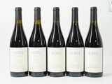 quatre bouteilles de vin sont alignées sur une surface blanche