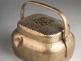 an old brass teapot with a handle on a white surface